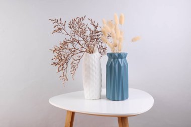 Kahve masasında kurumuş çiçekli vazolar.