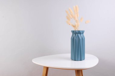 Kahve masasında kurumuş çiçekli vazo.