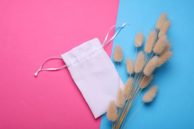 Kumaş poşet ürün ambalajlama ve mavi pembe arka planda kurutulmuş lagurus çiçekleri