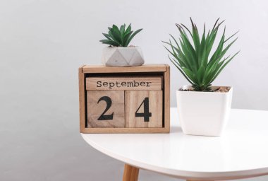 24 Eylül tarihli ahşap takvim düzenleyici ve masa üzerinde dekoratif bitkiler