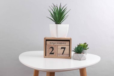 27 Eylül tarihli ahşap takvim düzenleyici ve masa üzerinde dekoratif bitkiler