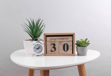 30 Eylül tarihli ahşap takvim düzenleyici ve dekoratif bitki, masa üzerinde çalar saat