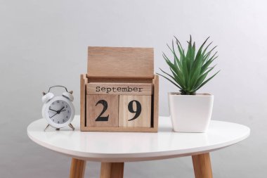 29 Eylül tarihli ahşap takvim düzenleyici ve dekoratif bitki, masa üzerinde çalar saat