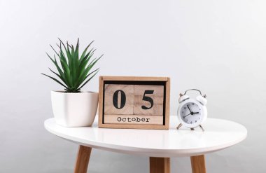 Tahta takvim düzenleyicisi. Tarih Ekim 05 ve masa üzerindeki çalar saat.