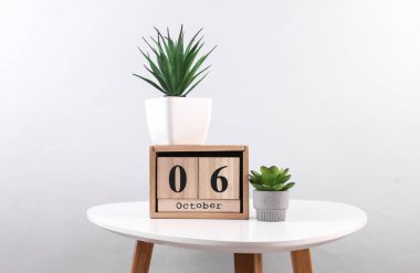 Ekim 06 tarihli ahşap takvim düzenleyici ve masa üzerinde dekoratif bitkiler