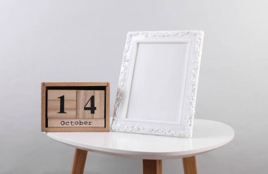 14 Ekim tarihli ahşap takvim düzenleyici ve masanın üzerinde fotoğraf çerçevesi