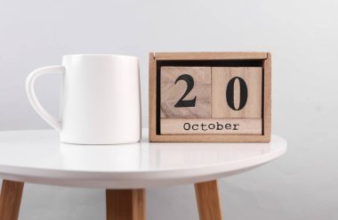 20 Ekim tarihli ahşap takvim düzenleyici ve masada seramik bardak