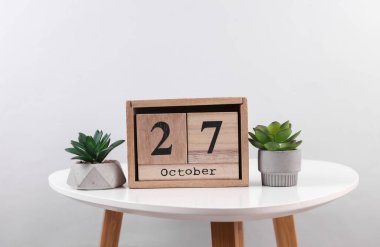27 Ekim tarihli ahşap takvim düzenleyici ve masa üzerinde dekoratif bitkiler