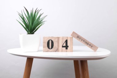 4 Kasım tarihli ahşap takvim düzenleyici ve masa üzerinde dekoratif bitki