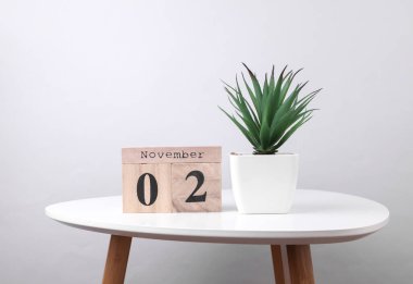 2 Kasım tarihli ahşap takvim düzenleyici ve masa üzerinde dekoratif bitki