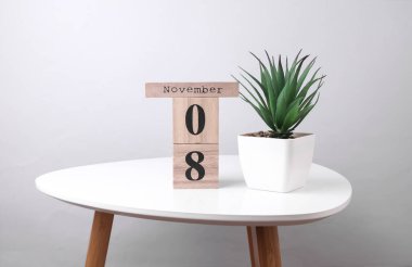 Wooden calendar organizer with date november 8 and decorative plant on table