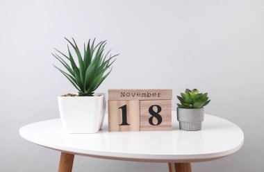 Wooden calendar organizer with date november 18 and decorative plants on table