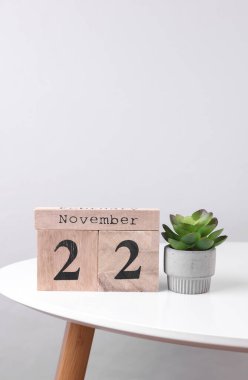 22 Kasım tarihli ahşap takvim düzenleyici ve masa üzerinde dekoratif bitki