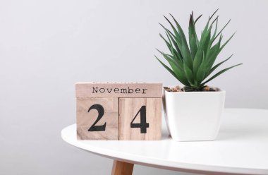 24 Kasım tarihli ahşap takvim düzenleyici ve masa üzerinde dekoratif bitki