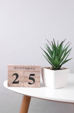 25 Kasım tarihli ahşap takvim düzenleyici ve masa üzerinde dekoratif bitki