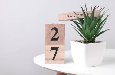27 Kasım tarihli ahşap takvim düzenleyici ve masa üzerinde dekoratif bitki