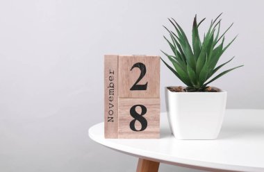 28 Kasım tarihli ahşap takvim düzenleyici ve masa üzerinde dekoratif bitki
