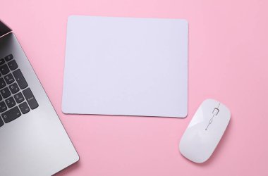 Aksesuarları, fare ve dizüstü bilgisayarı, pembe arka planı olan beyaz, boş bir bilgisayar fare altlığı. Üst Manzara. Düz yatıyordu