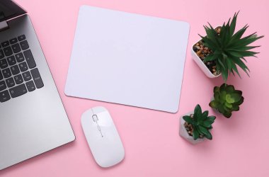 Aksesuarları, fare ve dizüstü bilgisayarı, pembe arka planı olan beyaz, boş bir bilgisayar fare altlığı. Üst Manzara. Düz yatıyordu