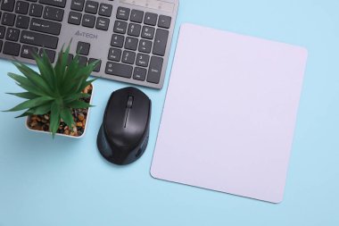 Mavi arkaplanda fare, fare ve klavye bulunan beyaz, boş bilgisayar fare altlığının bir kopyası. Üst Manzara. Düz yatıyordu