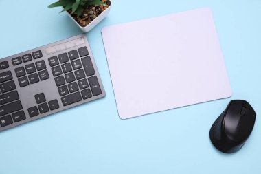 Mavi arkaplanda fare, fare ve klavye bulunan beyaz, boş bilgisayar fare altlığının bir kopyası. Üst Manzara. Düz yatıyordu