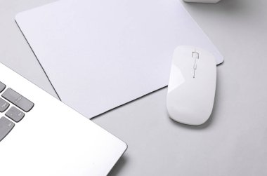 Gri arka planda beyaz, boş bilgisayar fare altlığı ya da aksesuarlı, fare ve dizüstü bilgisayarın bir kopyası. Üst Manzara. Düz yatıyordu