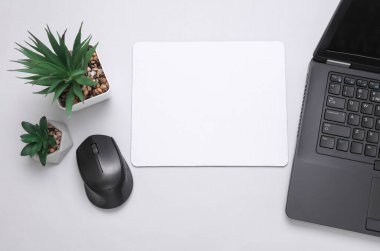 Gri arka planda beyaz, boş bilgisayar fare altlığı ya da aksesuarlı, fare ve dizüstü bilgisayarın bir kopyası. Üst Manzara. Düz yatıyordu