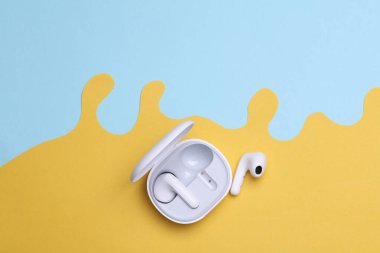 Kablosuz kulaklıklar. Yaratıcı kağıt arka planda şarj çantası var. Üst görünüm