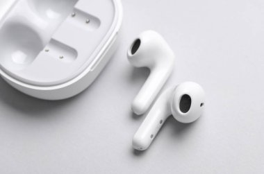 Wireless earphones with charging case on gray background.