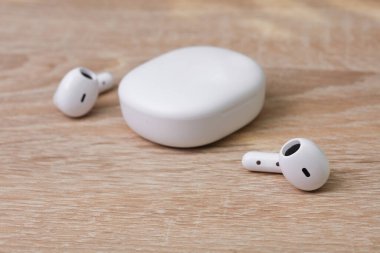 Masada şarj çantası olan beyaz kablosuz kulaklıklar.