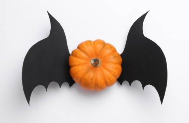 Beyaz arka planda yarasa kanatları olan bir balkabağı. Cadılar Bayramı el yapımı dekor