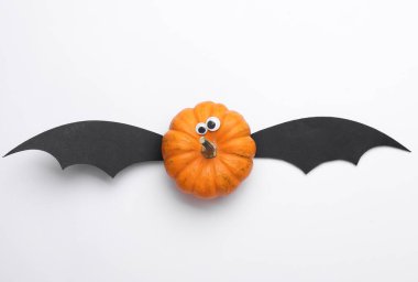 Beyaz arka planda yarasa kanatları olan bir balkabağı. Cadılar Bayramı el yapımı dekor