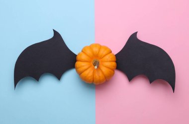 Pembe arka planda yarasa kanatları olan bir balkabağı. Cadılar Bayramı el yapımı dekor