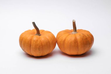 Beyaz arka planda iki doğal turuncu balkabağı.