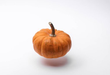 Beyaz arka planda yüzen doğal turuncu balkabağı