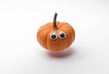 Beyaz arka planda süzülen şaşı gözlü balkabağı. Cadılar Bayramı dekoru, tatil için el yapımı, 31 Ekim. Üst görünüm