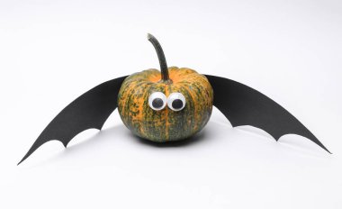 Yarasa kanatlı balkabağı ve beyaz arka planda şaşı gözler. Cadılar Bayramı el yapımı dekor