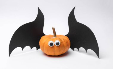 Yarasa kanatlı balkabağı ve beyaz arka planda şaşı gözler. Cadılar Bayramı el yapımı dekor