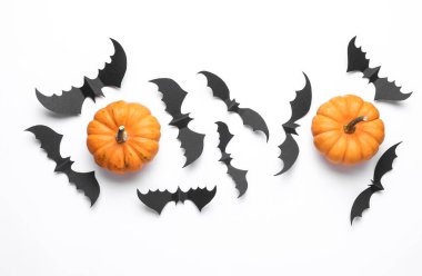 Paper cut black bats and pumpkins on white background. Halloween decor