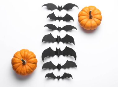 Paper cut black bats and pumpkins on white background. Halloween decor