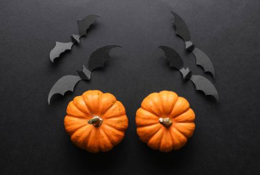 Paper cut black bats and pumpkins on black background. Halloween decor. Flat lay