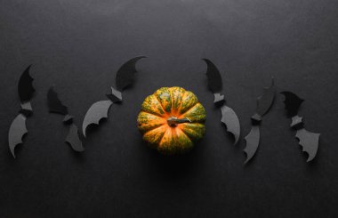 Paper cut black bats and pumpkin on black background. Halloween decor