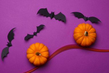 El yapımı kağıt cadılar bayramı sahnesini mor arka planda yarasalar ve balkabağı ile keser