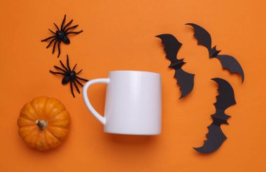 Tasarımınız için beyaz seramik kupa modeli ve turuncu arkaplanda Cadılar Bayramı dekoru