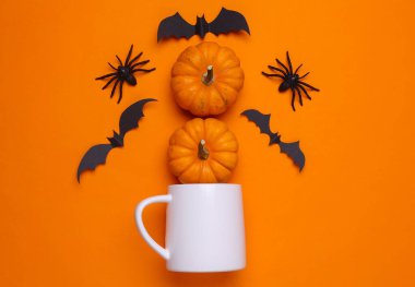 Tasarımınız için beyaz seramik kupa modeli ve turuncu arkaplanda Cadılar Bayramı dekoru