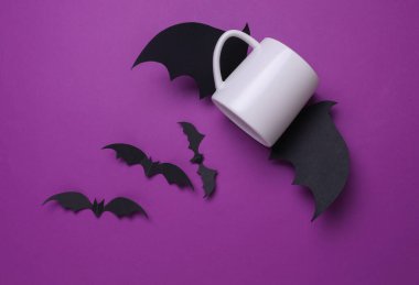 Tasarımınız için beyaz seramik kupa ve mor arka planda Cadılar Bayramı dekoratif yarasalar