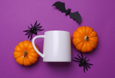 Tasarımınız için beyaz seramik kupa ve mor arka planda Cadılar Bayramı dekoru