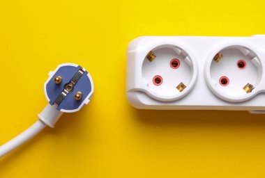 Beyaz elektrik uzatma kablosu ve sarı fişin fişi.