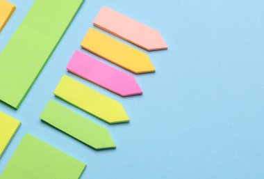 Çeşitli boş kağıt çıkartmaları var. Çok renkli. Mavi arkaplanda yapışkan not koleksiyonu