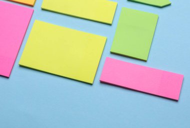 Çeşitli boş kağıt çıkartmaları var. Çok renkli. Mavi arkaplanda yapışkan not koleksiyonu